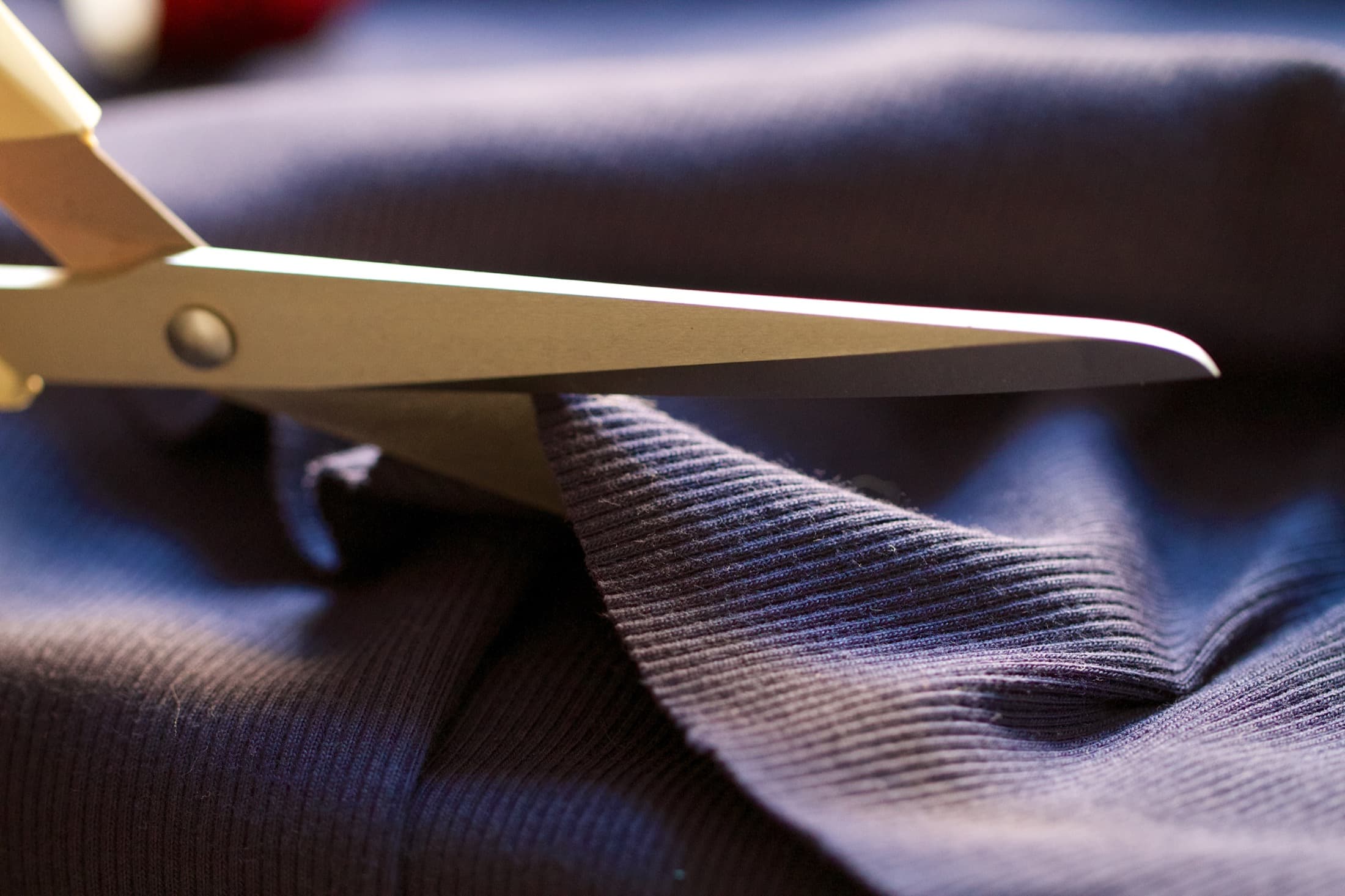 Tailor's shears cutting through folded navy fabric