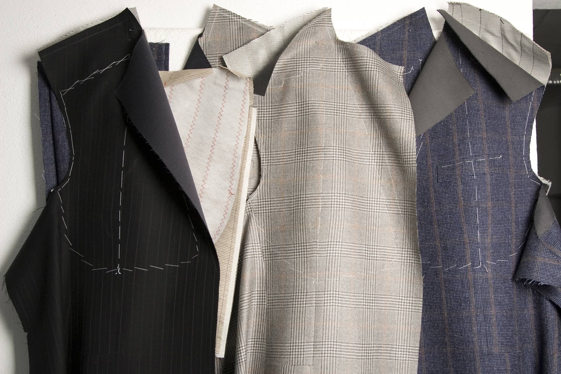 Cut suit pattern pieces and fabric hanging in the workshop