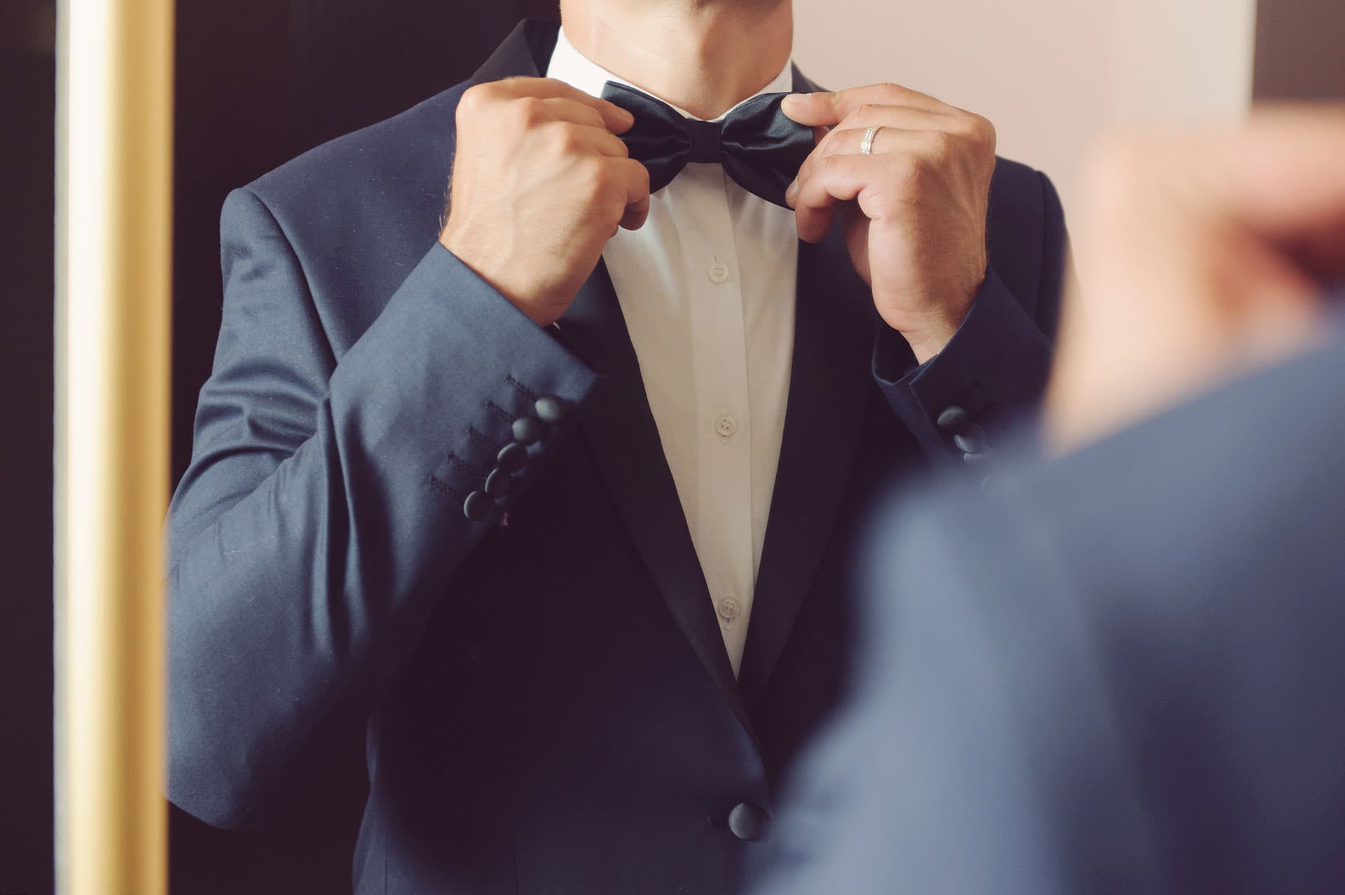 Hands tying a black bow tie